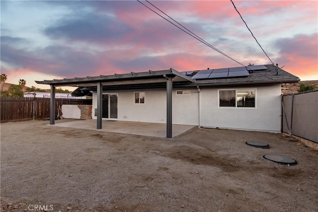 back house at dusk featuring a patio