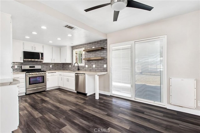 kitchen featuring appliances with stainless steel finishes, white cabinetry, ceiling fan, backsplash, and dark wood-type flooring