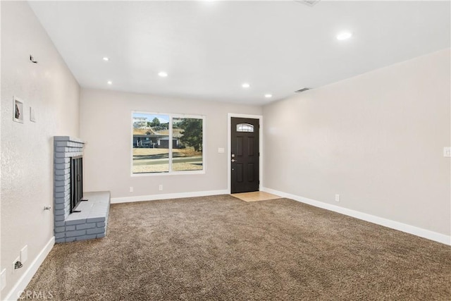 unfurnished living room featuring a brick fireplace and carpet flooring