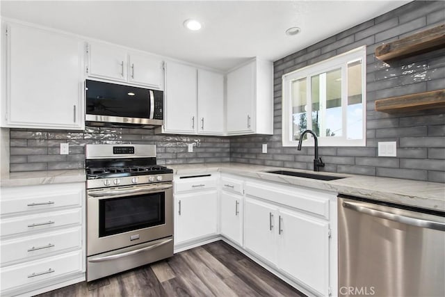 kitchen featuring light stone counters, dark wood-type flooring, stainless steel appliances, white cabinets, and sink