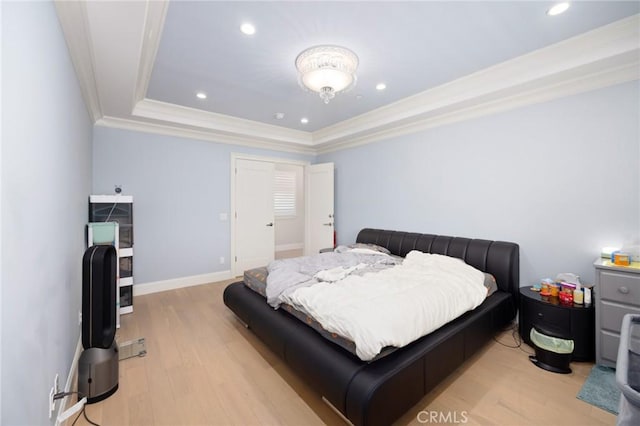 bedroom featuring a raised ceiling, light hardwood / wood-style flooring, and ornamental molding