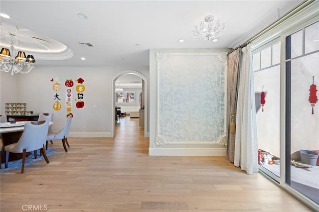 interior space with a tray ceiling, light hardwood / wood-style flooring, and a chandelier