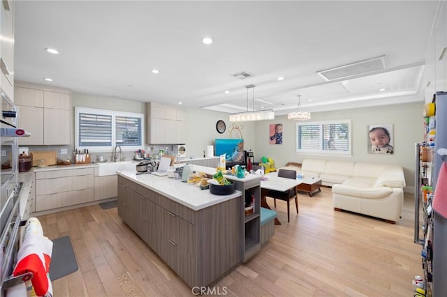 kitchen featuring sink, a center island, hanging light fixtures, light hardwood / wood-style flooring, and white cabinets