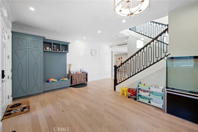 recreation room with light hardwood / wood-style floors, ornamental molding, and an inviting chandelier