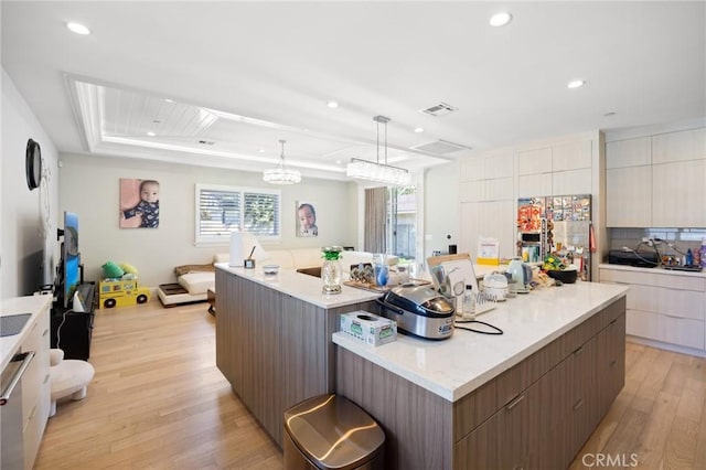 kitchen with stainless steel fridge with ice dispenser, decorative light fixtures, light hardwood / wood-style flooring, and a large island