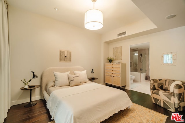 bedroom with ensuite bath and dark hardwood / wood-style flooring