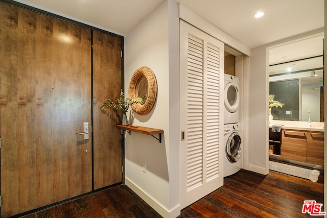 laundry area with stacked washer and dryer, dark wood-type flooring, and sink