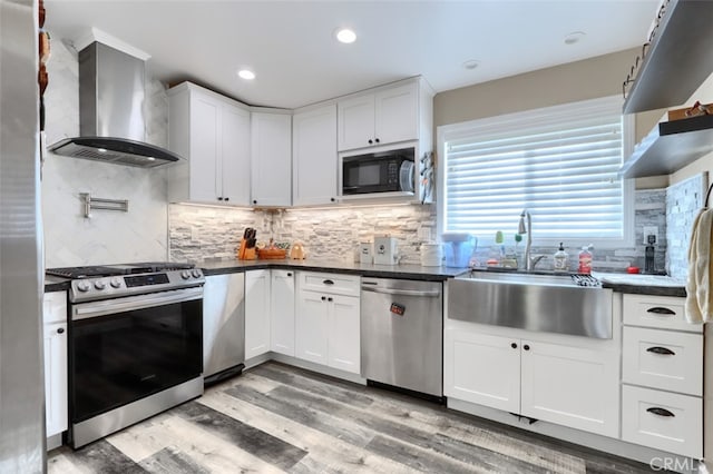 kitchen with sink, white cabinets, wall chimney range hood, and appliances with stainless steel finishes