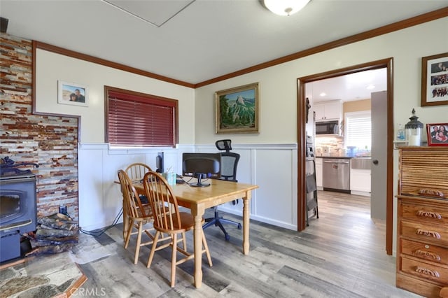 dining area with light wood-type flooring, a wood stove, and crown molding