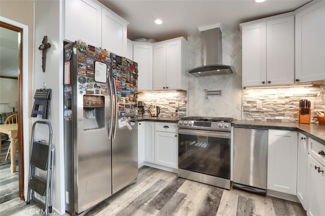 kitchen featuring white cabinets, appliances with stainless steel finishes, and wall chimney range hood