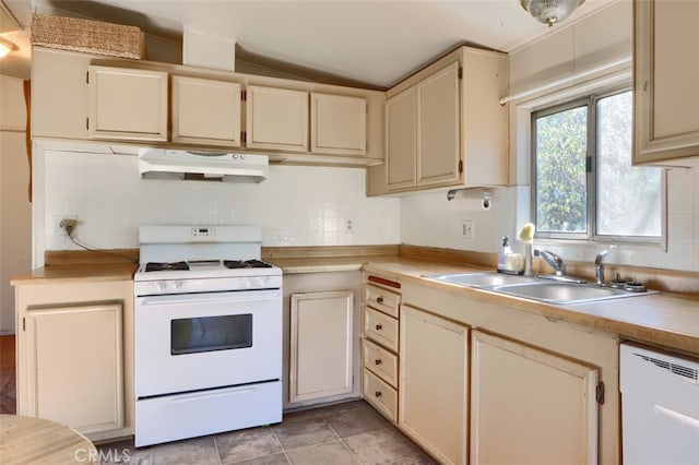 kitchen featuring tasteful backsplash, white appliances, vaulted ceiling, sink, and cream cabinetry