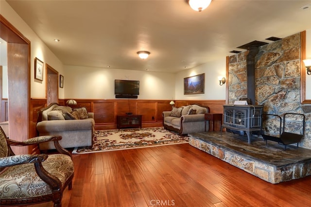 living room featuring hardwood / wood-style floors, a wood stove, and wood walls