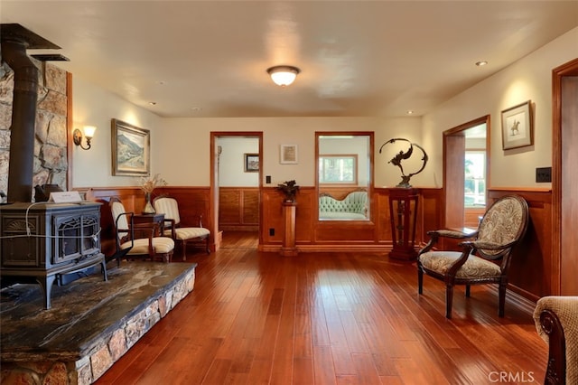 sitting room featuring hardwood / wood-style flooring, wood walls, and a wood stove