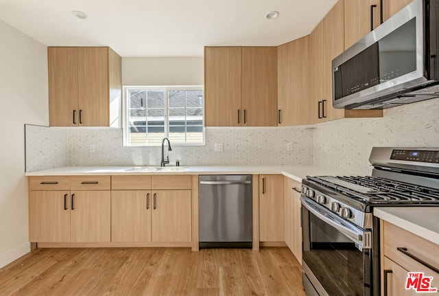 kitchen featuring sink, backsplash, light hardwood / wood-style floors, light brown cabinetry, and appliances with stainless steel finishes