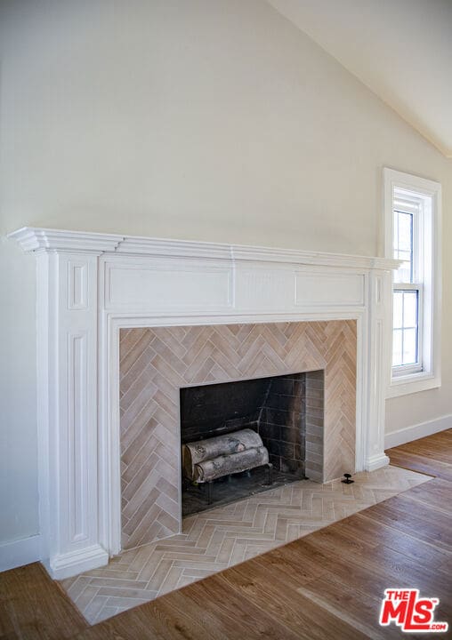 interior details featuring wood-type flooring and a tiled fireplace