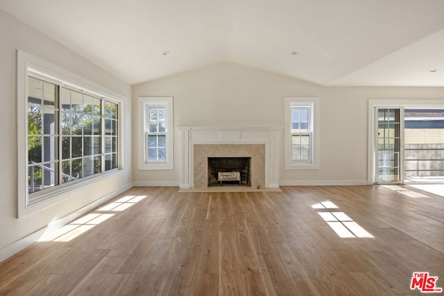 unfurnished living room with light wood-type flooring, a fireplace, and vaulted ceiling