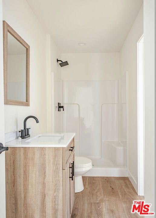 bathroom featuring hardwood / wood-style flooring, vanity, toilet, and walk in shower