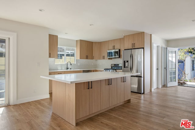 kitchen with stainless steel appliances, a kitchen island, and light hardwood / wood-style floors