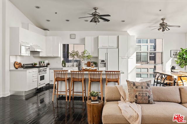 kitchen with white cabinets, a kitchen bar, dark hardwood / wood-style flooring, and high quality appliances