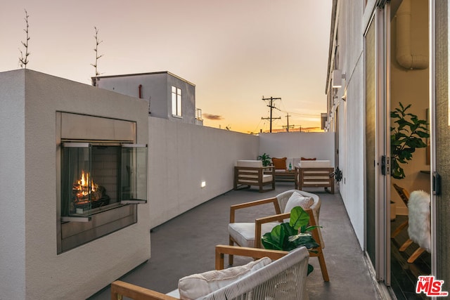 patio terrace at dusk featuring an outdoor living space with a fireplace