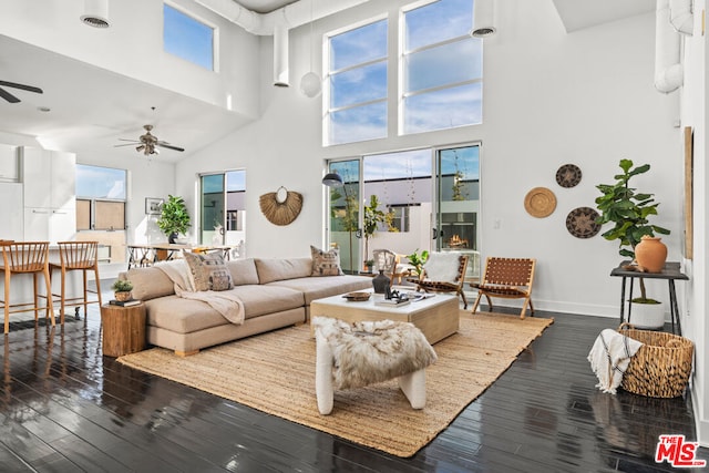 living room featuring ceiling fan, a towering ceiling, and dark hardwood / wood-style floors