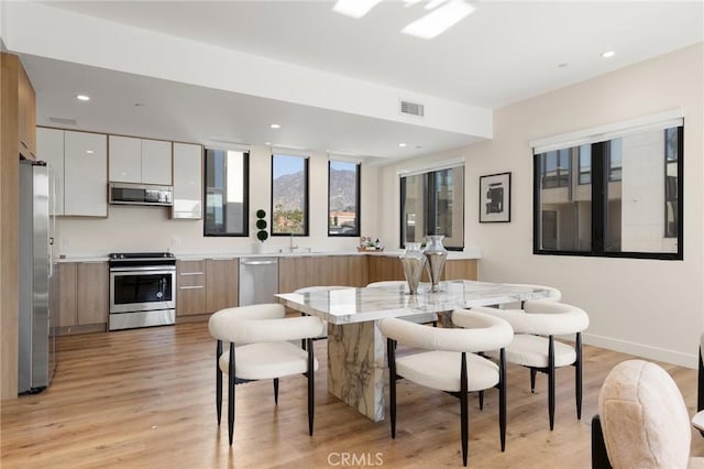 dining space with sink and light hardwood / wood-style floors