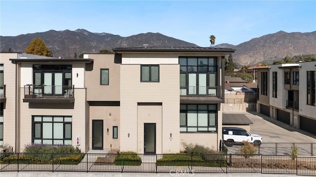 view of front of house featuring a fenced front yard, a mountain view, a garage, concrete driveway, and stucco siding