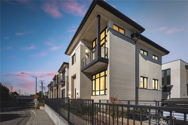 property exterior at dusk featuring a balcony