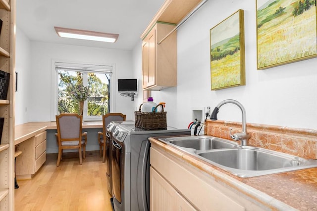 washroom featuring cabinets, sink, washing machine and clothes dryer, and light wood-type flooring