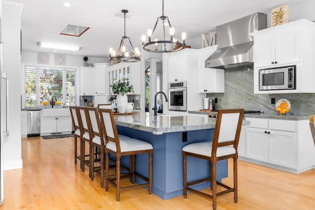 kitchen featuring a kitchen island, pendant lighting, tasteful backsplash, stainless steel appliances, and wall chimney range hood