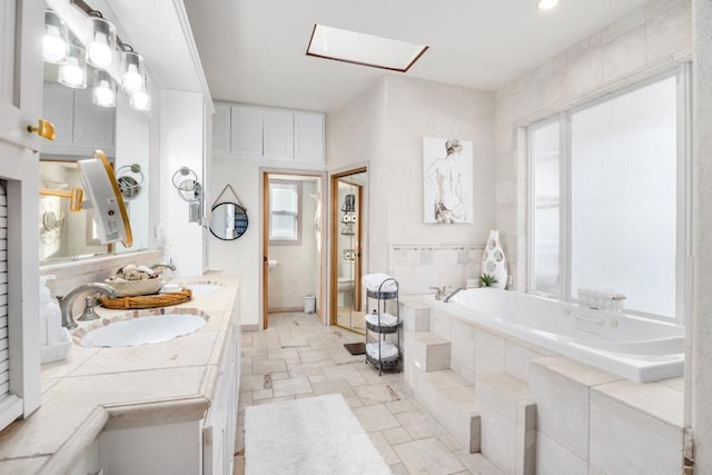 bathroom with vanity, tiled tub, a wealth of natural light, and toilet