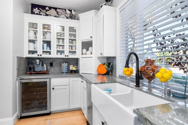 kitchen featuring white cabinetry, sink, wine cooler, and light stone counters