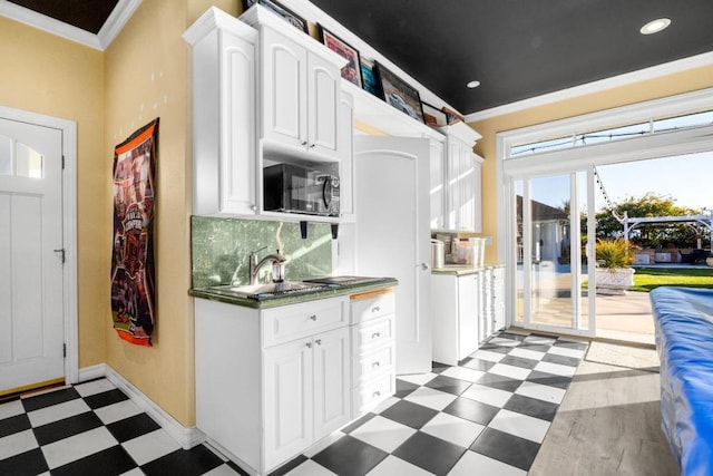 kitchen with backsplash, ornamental molding, sink, and white cabinets