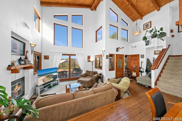 living room with beam ceiling, wooden ceiling, a high ceiling, and hardwood / wood-style flooring