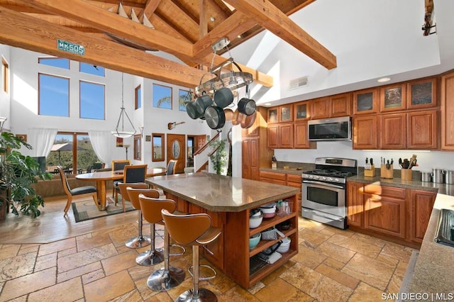 kitchen featuring stainless steel appliances, beamed ceiling, hanging light fixtures, high vaulted ceiling, and a center island