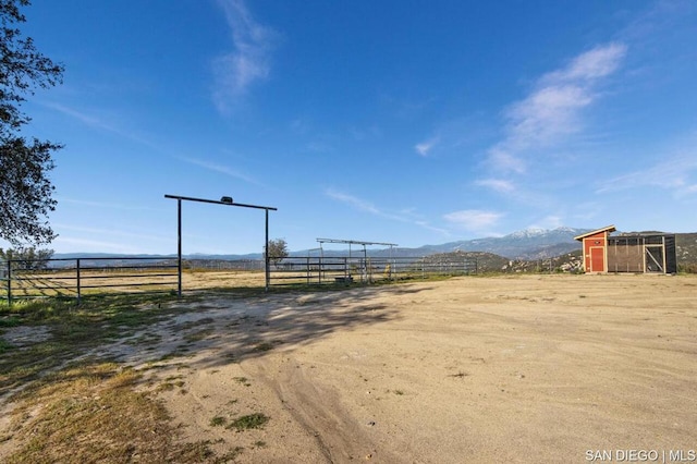 view of yard with a mountain view, an outbuilding, and a rural view