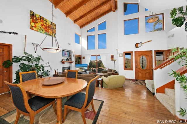 dining area with high vaulted ceiling, beam ceiling, light wood-type flooring, and wooden ceiling