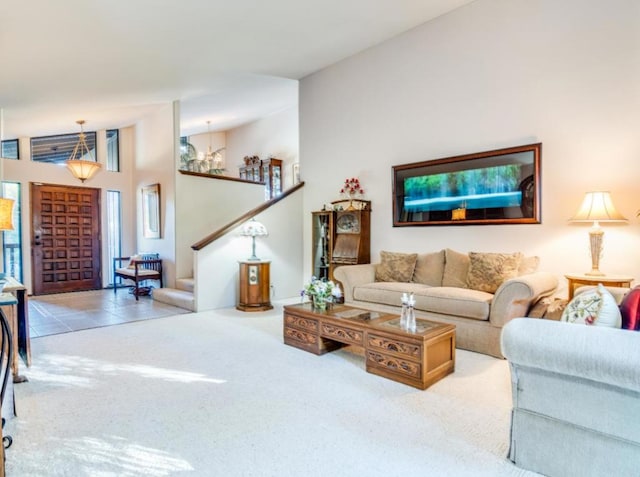 carpeted living room with an inviting chandelier and high vaulted ceiling