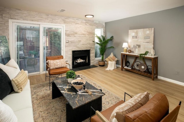 living room featuring a stone fireplace and wood-type flooring