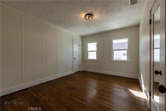 spare room with a textured ceiling and dark hardwood / wood-style floors