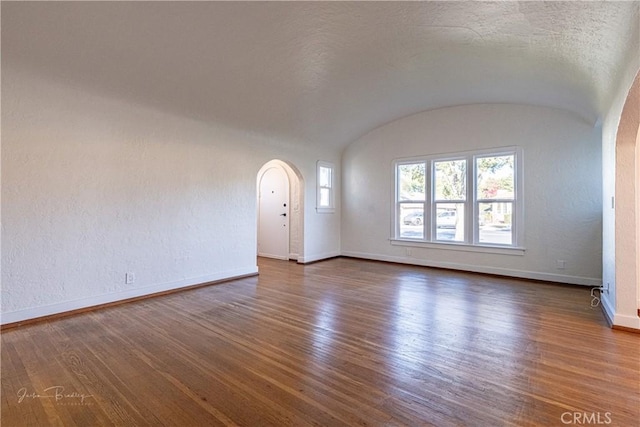 interior space featuring dark hardwood / wood-style flooring, lofted ceiling, and brick ceiling