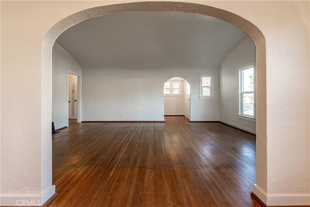 spare room with dark hardwood / wood-style flooring and vaulted ceiling