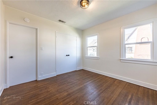 unfurnished bedroom with dark hardwood / wood-style floors and a closet