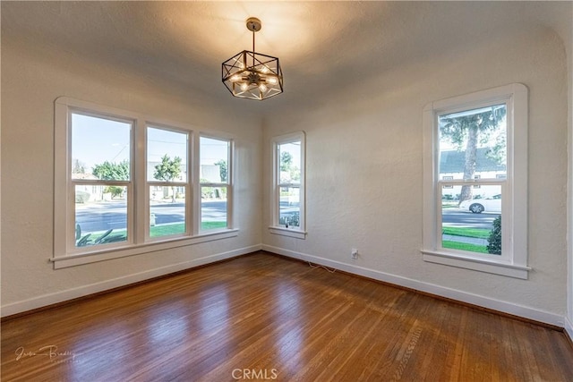 empty room with hardwood / wood-style floors and a chandelier