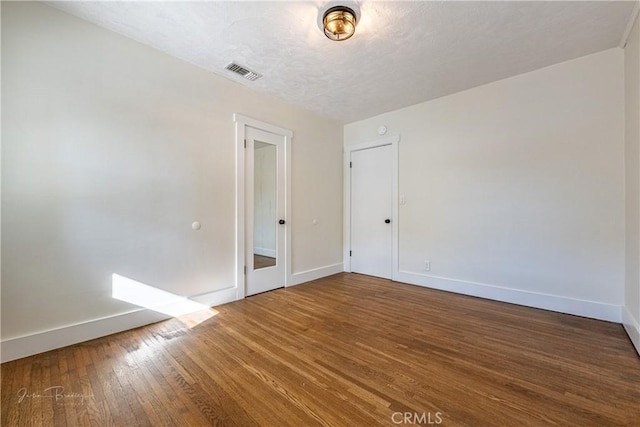 unfurnished room featuring a textured ceiling and hardwood / wood-style flooring