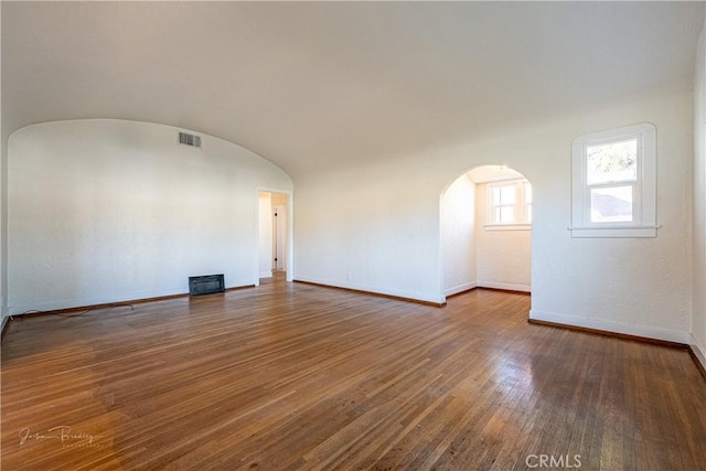 unfurnished room with dark hardwood / wood-style floors, brick ceiling, and vaulted ceiling