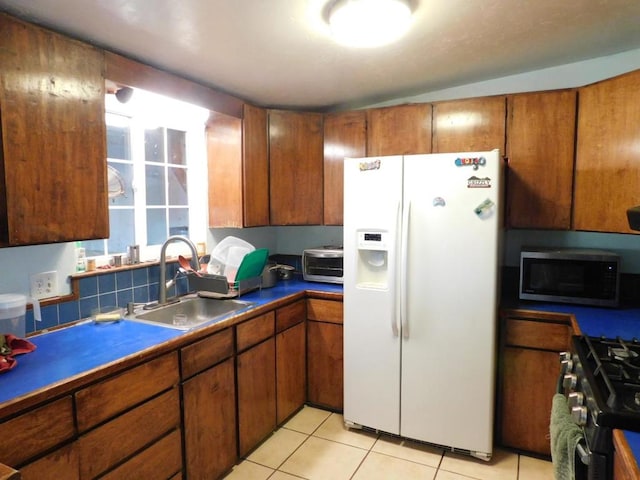 kitchen with appliances with stainless steel finishes, light tile patterned floors, and sink