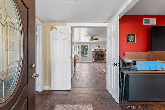 entryway with ceiling fan, dark hardwood / wood-style flooring, and a brick fireplace