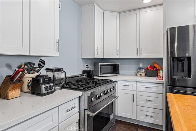 kitchen with white cabinetry, stainless steel appliances, and wooden counters