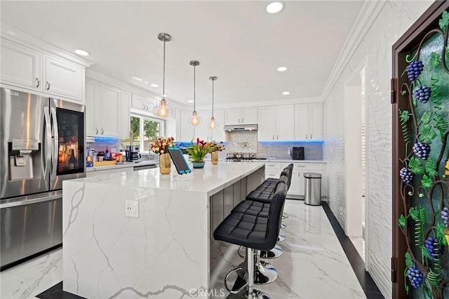 kitchen featuring a center island, stainless steel appliances, white cabinetry, and ornamental molding